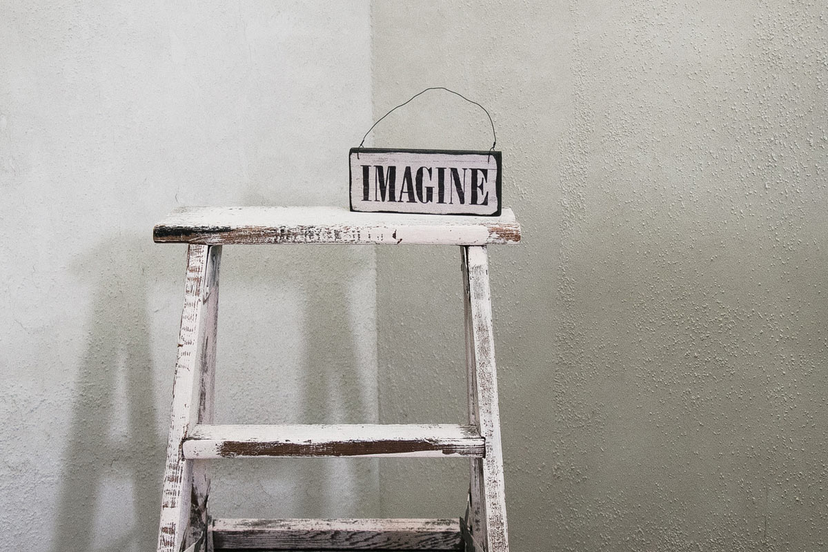Wooden ladder with paint marks in from of two meeting walls and a sign spelling the word IMAGINE. Imagine you would know the budget and steps needed to grow your brand online.